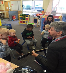 children listening to teacher playing guitar